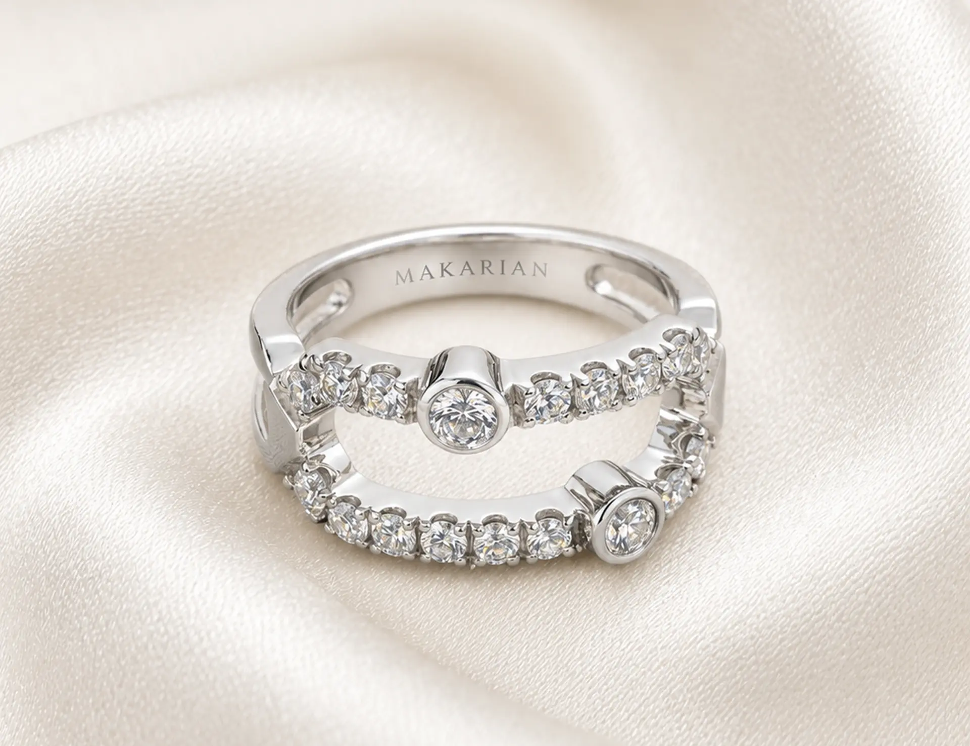 Finished MAKARIAN double-band diamond ring resting on ivory silk