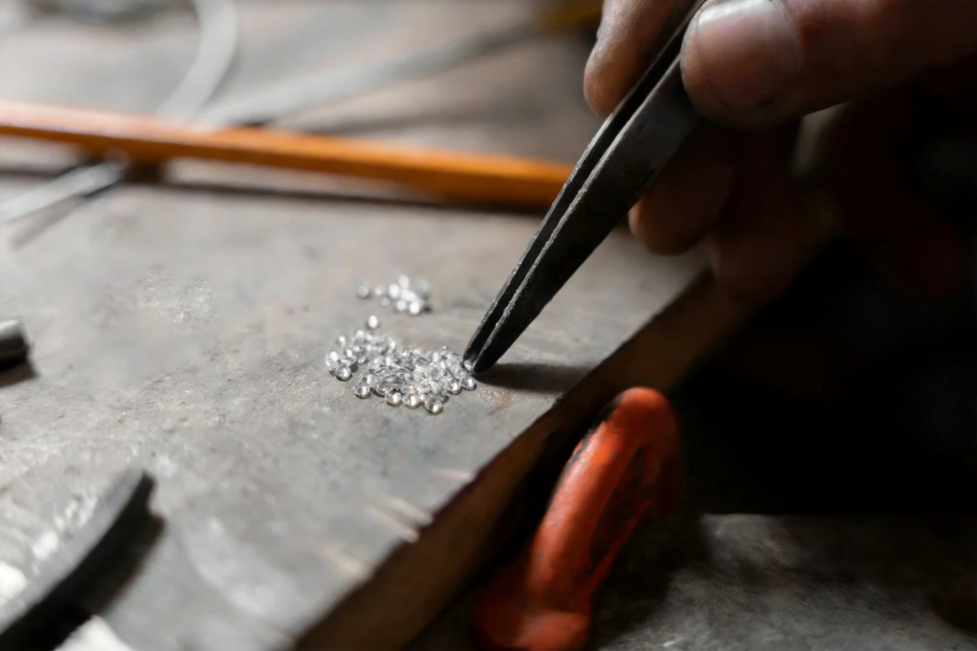 A jeweller sorting loose diamonds with tweezers on a workbench