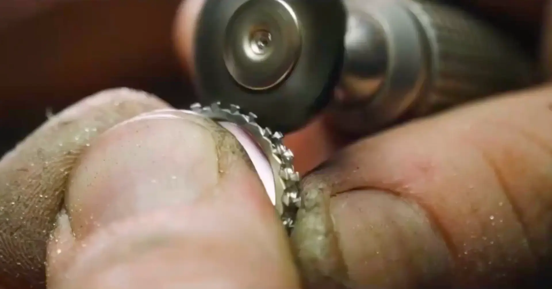 Close-up of a jeweller polishing a diamond-set ring with a rotary tool