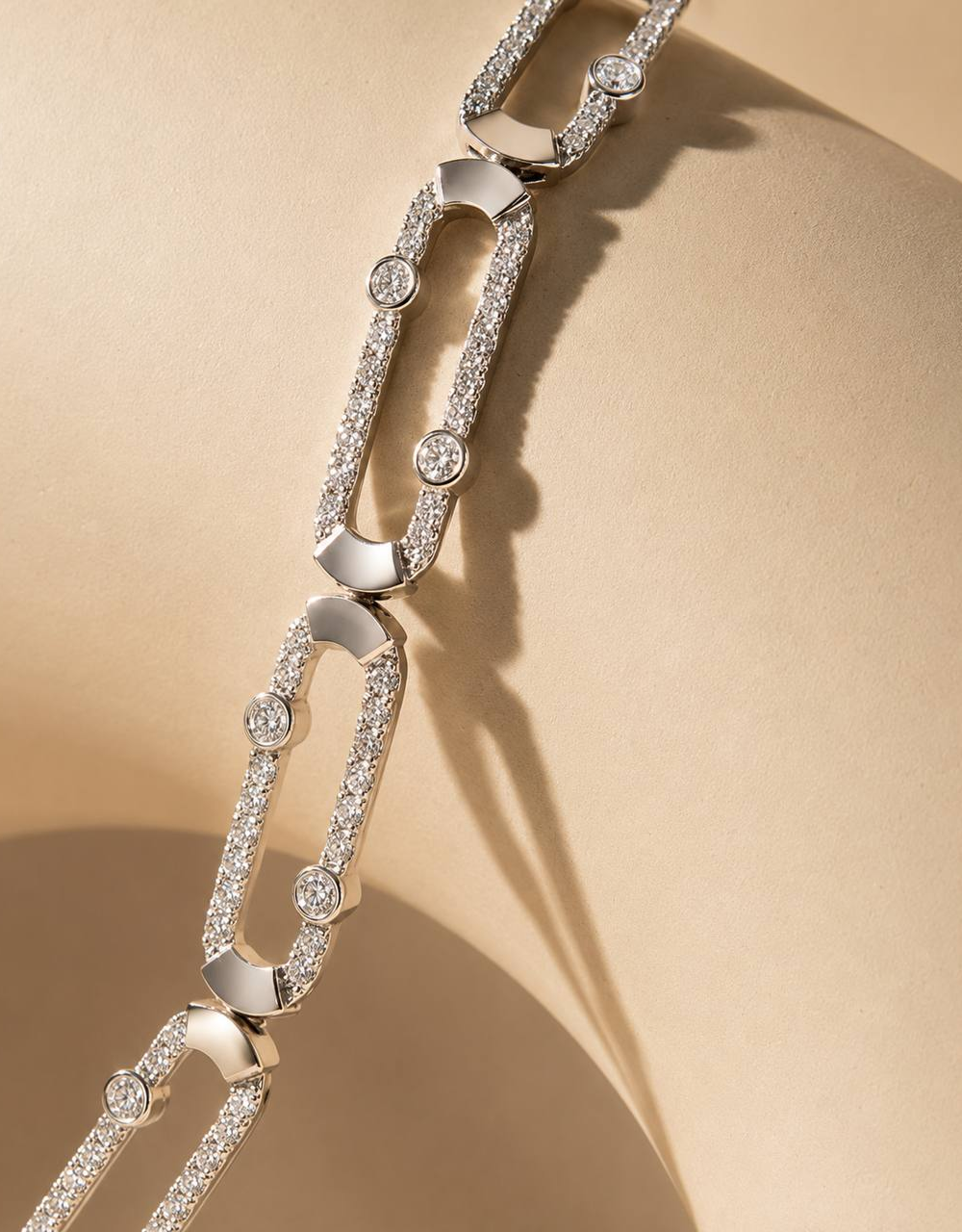 Diamond-set white gold link necklace on a warm sand backdrop