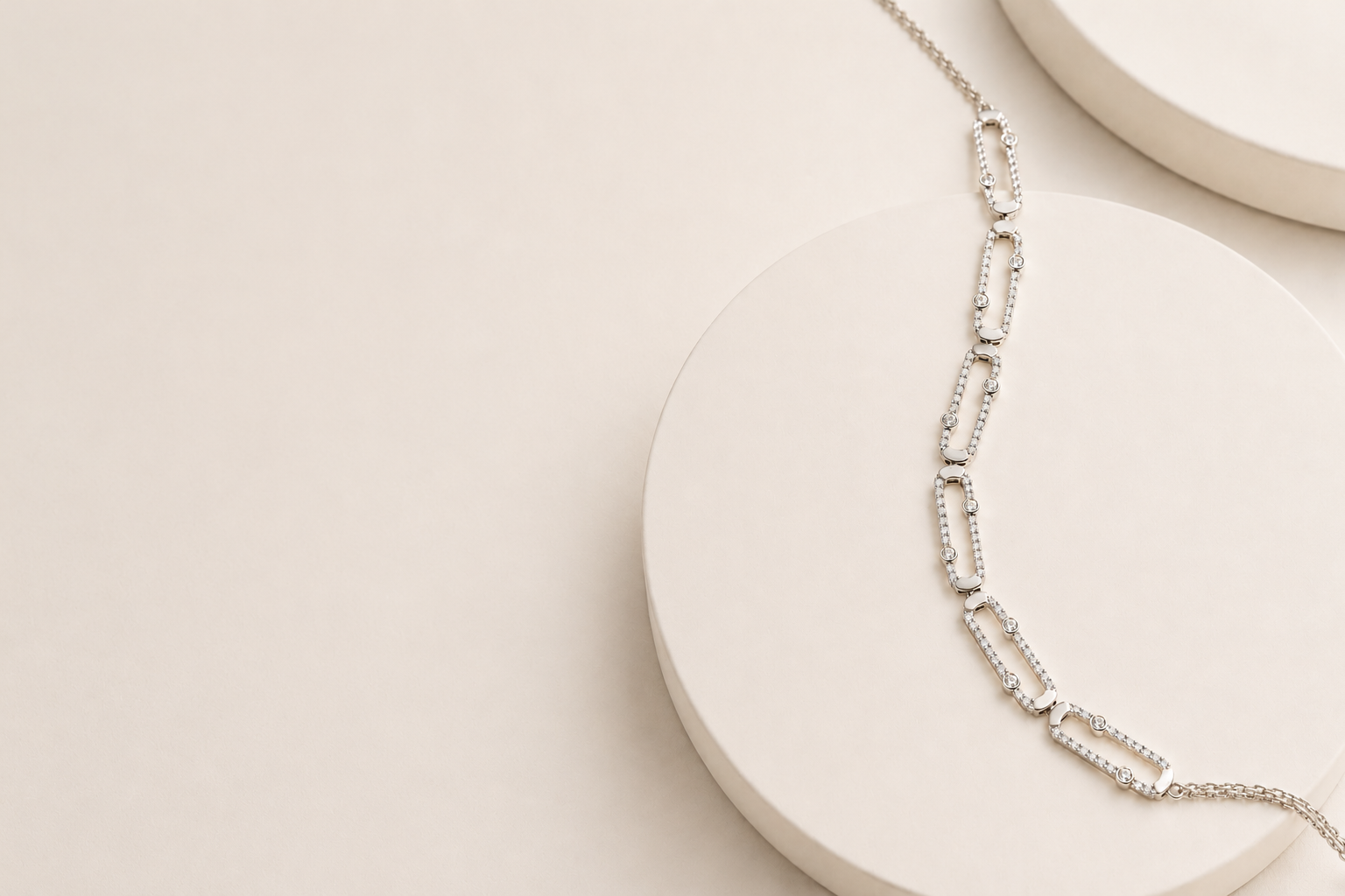 A diamond-set white gold link necklace draped over a pale stone plinth